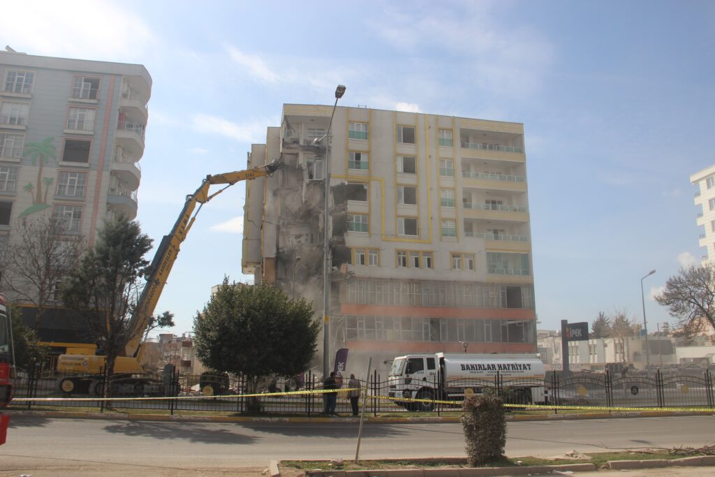 Yıkımı gerçekleştirilen bina, iş makinesinin üzerine devrildi